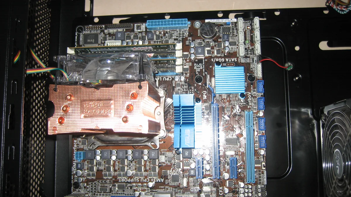 A motherboard with a copper CPU cooler installed inside a computer case